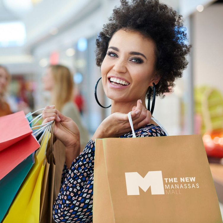 Smiling shopper carrying Manassas Mall shopping bags